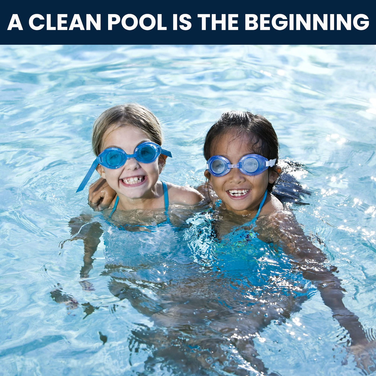 Two children in goggles smiling in a swimming pool.