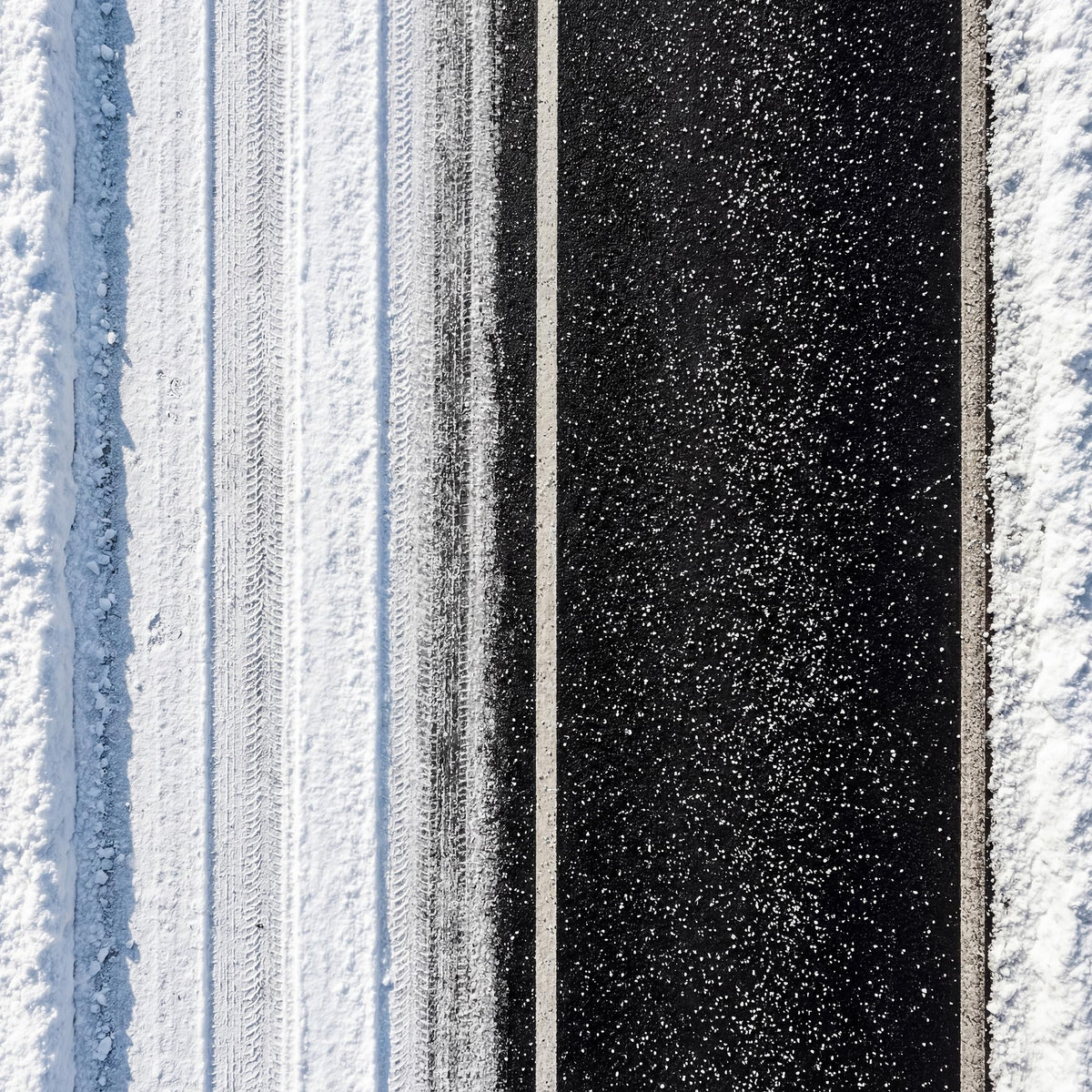 Overhead view of white salt spread down a dark driveway between snow.