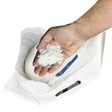 Hand holding fine white pool salt over an open bag.