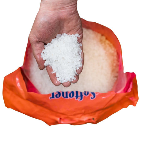 Hand holding white solar coarse crystals over an open Softener Shield Salt bag.
