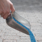 Scoop pouring blue Emperor Melt ice melt granules onto a paver walkway.