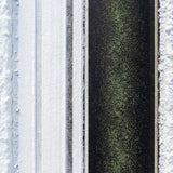 Overhead view of green ice melt granules spread down a dark driveway between snow.